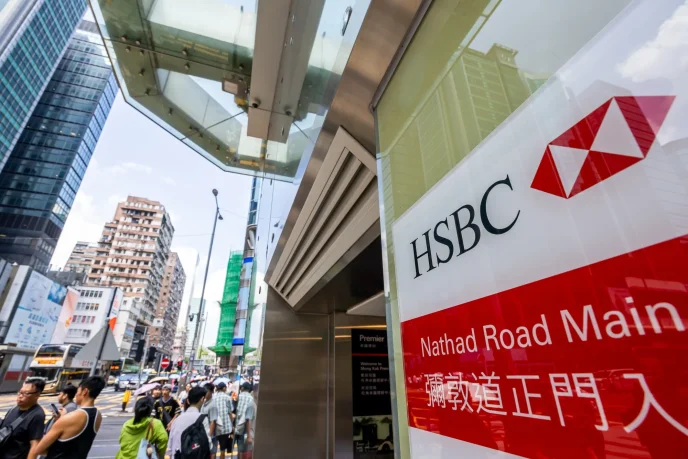 Glass storefront with an HSBC sign and red banner reading Nathan Road Main, busy street scene with pedestrians and tall buildings in a city.