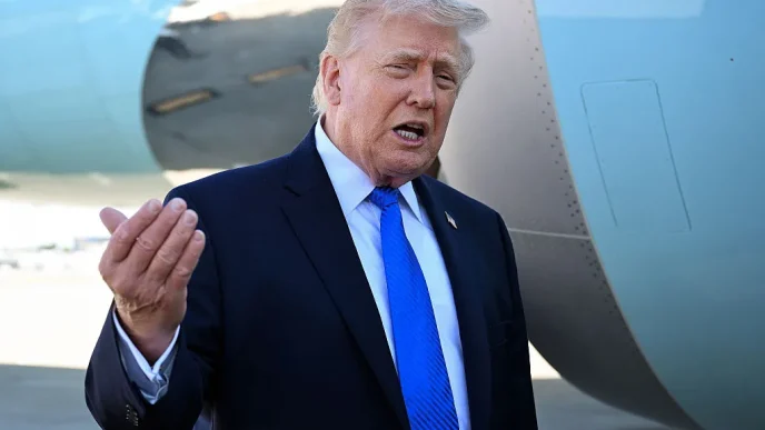 Man in a dark suit and blue tie gesturing while speaking next to a large aircraft fuselage.