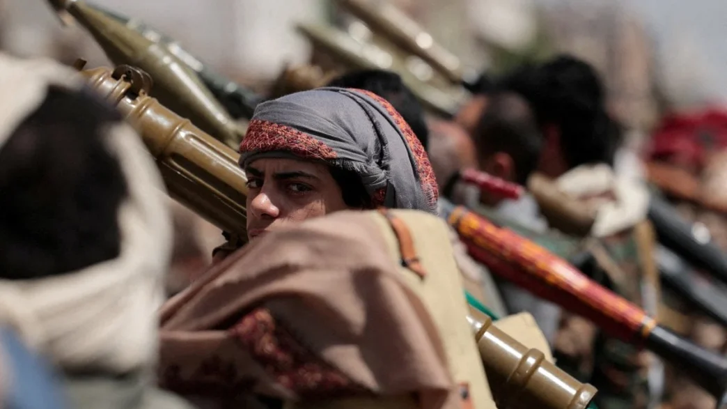 Houthi fighters carrying weapons in a line