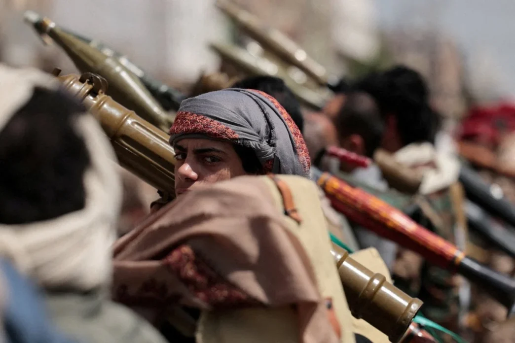 Houthi fighters carrying weapons in a line