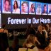 Mourners gather before a memorial screen displaying photos of October 7 victims